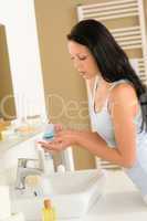 Woman cleaning face with cotton pad bathroom