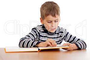 Cute schoolboy is reading a book
