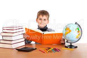 Cute schoolboy is reading a book