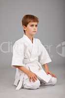 Karate boy in white kimono is sitting