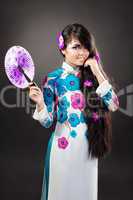 Beautiful asian woman wears a national dress is holding a fan