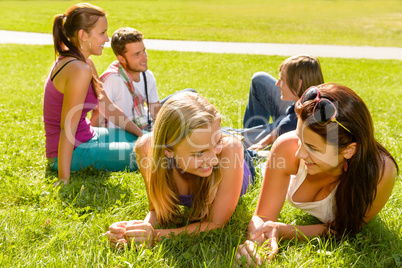 Teens talking relaxing on grass in park