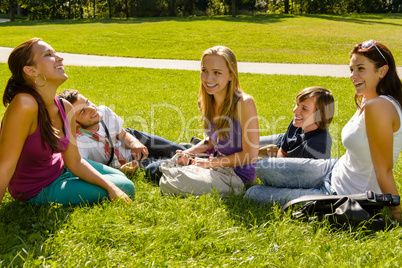 Teens sitting on lawn in park talking