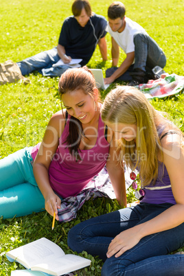 Teens studying in park reading book students
