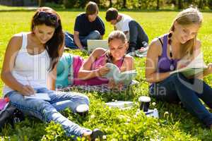 Teens studying in park reading book students