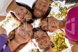 Teens in a circle smiling in park
