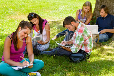 Students sitting in park studying reading writing
