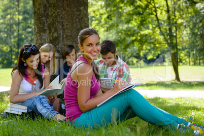 Students studying on meadow in park teens