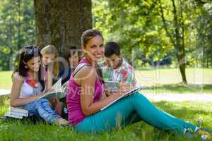 Students studying on meadow in park teens