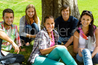 Students relaxing on meadow in park teens