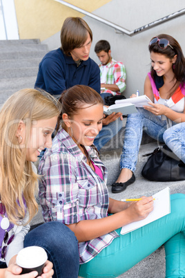 Students sitting on school steps writing studying