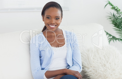 Black woman sitting on a sofa looking at camera