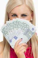Green eyed woman holding 100 euros banknotes