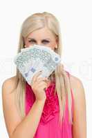 Blonde in pink holding 100 euros banknotes