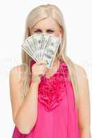 Serious hiding her face with 100 dollars banknotes