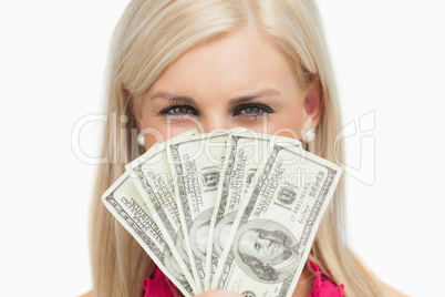 Smiling blonde hiding her face with 100 dollars banknotes
