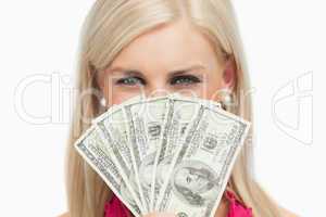 Smiling blonde hiding her face with 100 dollars banknotes