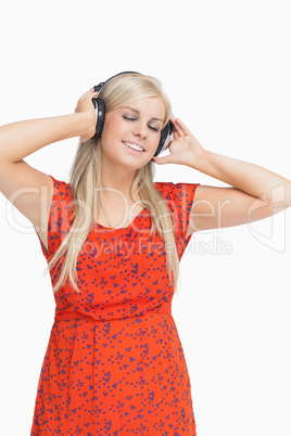 Smiling blonde in orange dress listening to music