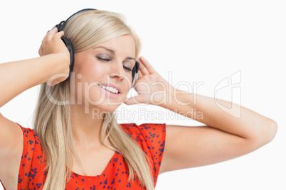 Happy blonde in orange dress listening to music