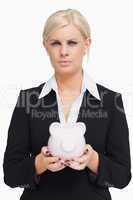 Serious businesswoman holding a piggy-bank