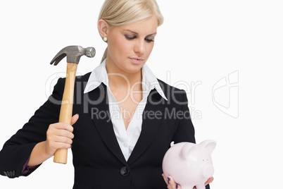 Serious businesswoman holding a piggy-bank and hammer