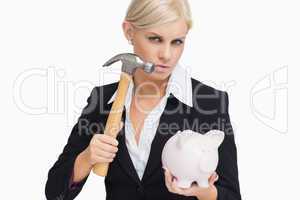 Stern businesswoman holding a hammer and a piggy-bank