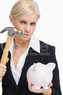 Beautiful businesswoman holding a hammer and a piggy-bank