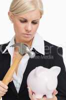 Sad businesswoman holding a hammer and a piggy-bank