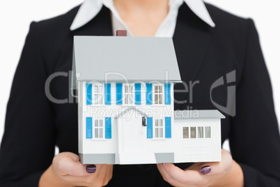 Smiling businesswoman holding a model house
