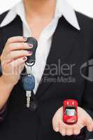 Woman holding key and small car in her palm
