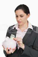 Brunette putting dollars into a piggy-bank