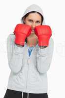 Serious brunette in sweatshirt wearing boxing gloves