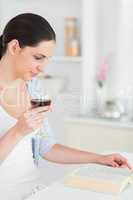 Woman reading while holding a red wine glass