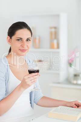 Woman reading and holding red wine glass