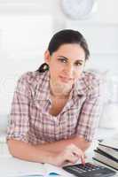 Woman using a calculator while looking at camera