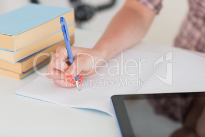 Woman writing on notepad with tablet pc