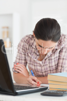 Woman writing on a notebook next to laptop
