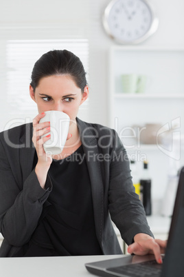 Woman using a laptop while drinking