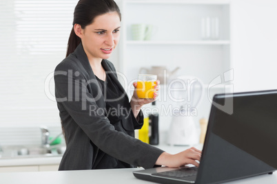 Woman looking at a laptop while holding a juice glass