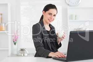 Smiling woman in front of laptop with glass of milk