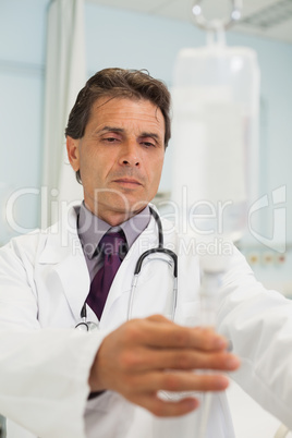 Thoughtful doctor in a hospital adjusting IV