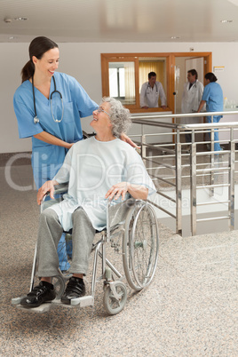 Nurse smiling at old women sitting in wheelchair