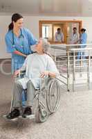 Nurse laughing with old women sitting in wheelchair