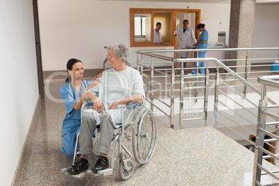 Nurse kneeling beside  old women sitting in wheelchair
