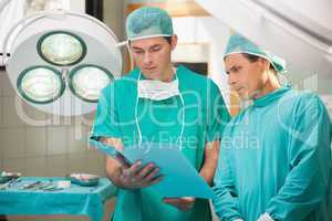Two surgeons studying file in operating theatre