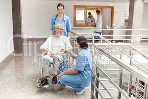 Two nurses looking after old women sitting in wheelchair