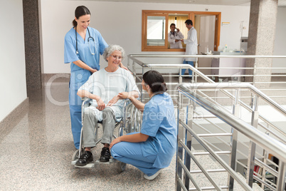 Two nurses talking with  old women sitting in wheelchair