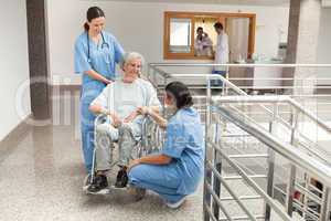 Two nurses talking with  old women sitting in wheelchair