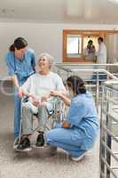 Old woman in wheelchair talking with nurses