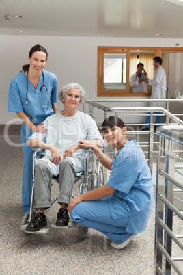 Two nurses with old woman in wheelchair